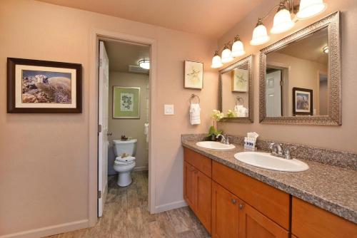a bathroom with two sinks and a mirror and a toilet at Napili Point C21 · NP C21 OceanFront 2BD Condo w AC Ocean Views in Kahana