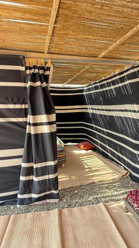 a bed with a black and white curtain on it at Jabreen Castle Camp in Naţţālah