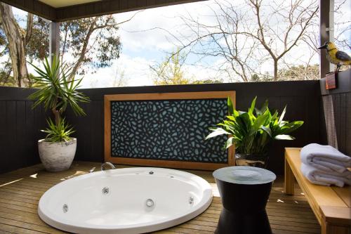 a bath tub sitting on top of a wooden deck at Daylesford Spa Villa 6 in Daylesford