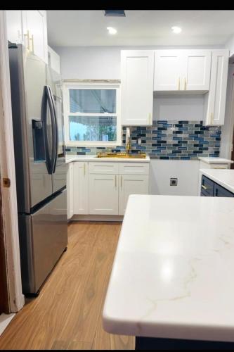 a kitchen with white cabinets and a black refrigerator at Belmont Lux Escape in Elmont