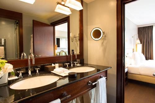 a bathroom with two sinks and a large mirror at La Réserve Genève Hotel & Spa in Geneva