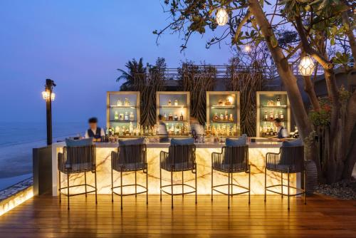 a restaurant with chairs and a bar at night at V Villas Hua Hin - MGallery Collection in Hua Hin