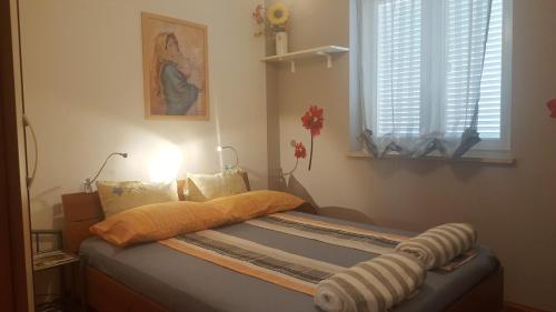 a bedroom with a bed with an orange pillow and a window at Apartment Mihaela in Rovinj
