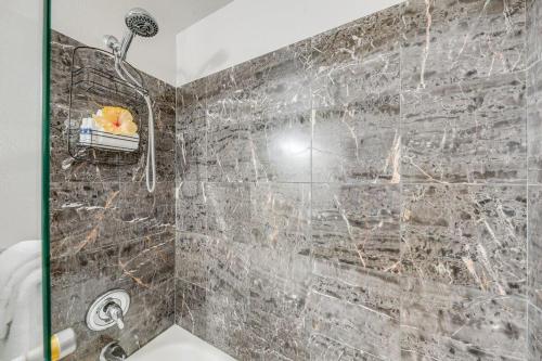 a bathroom with a shower with a stone wall at Kihei Alii Kai C405 · KAK C405 Updated 2BD Condo Across Beach w in Kihei