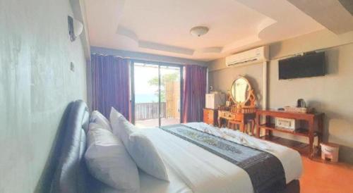 a bedroom with a large bed and a window at Jirawan Hotel in Ko Samed