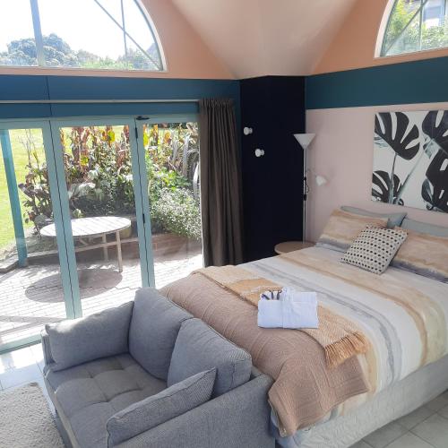 a bedroom with a large bed and a couch at The Quarters Ocean-View Chalet in Gisborne