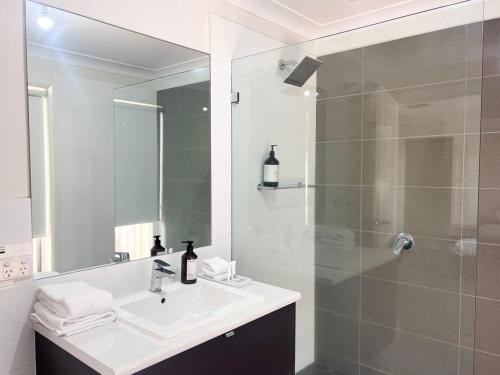 a white bathroom with a sink and a shower at Urban 3BR Oasis: Style & Comfort in Wagga Wagga