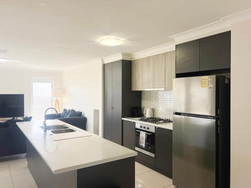 a kitchen with a stainless steel refrigerator and a stove at Urban 3BR Oasis: Style & Comfort in Wagga Wagga