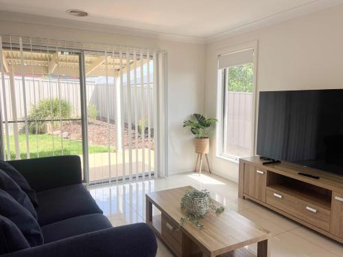 a living room with a couch and a flat screen tv at Urban 3BR Oasis: Style & Comfort in Wagga Wagga