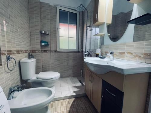 a bathroom with a toilet and a sink and a mirror at Paco Apartment Center Shkoder in Shkodër