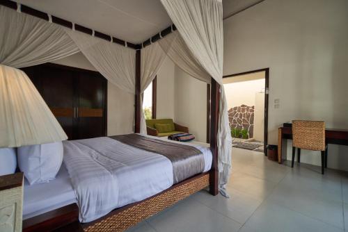 a bedroom with a canopy bed and a desk at 3Bedroom Umasari Villa in Keramas