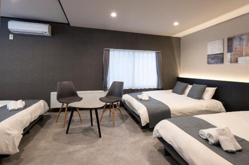 a room with three beds and a table and chairs at Central Stay Sapporo 札幌中心部 最大24名 キッズルーム in Sapporo