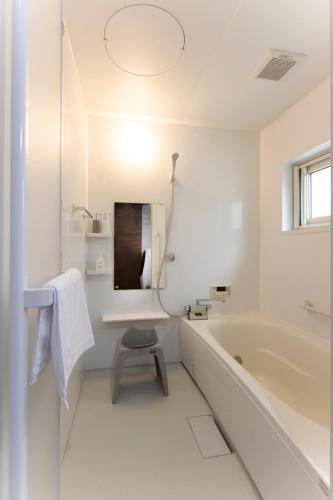 a white bathroom with a tub and a stool at Central Stay Sapporo 札幌中心部 最大24名 キッズルーム in Sapporo