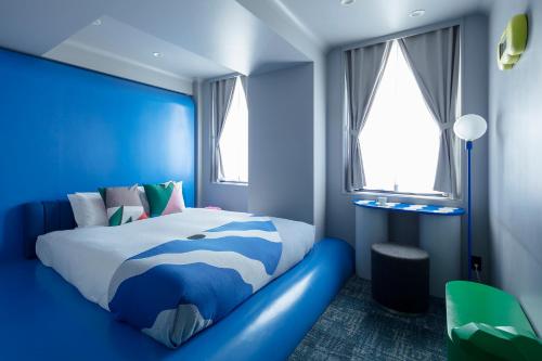 a blue bedroom with a bed in a room with windows at BnA WALL in Tokyo