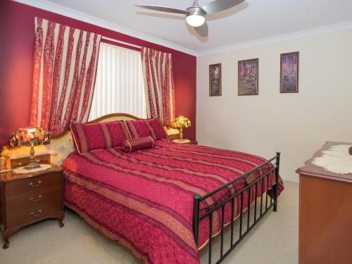 um quarto com uma cama grande e uma colcha vermelha em Ascot on Swan Bed & Breakfast em Perth