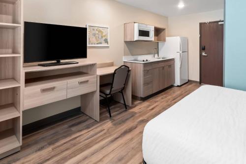 a hotel room with a bed and a desk with a television at WoodSpring Suites Greenville Airport in Greenville