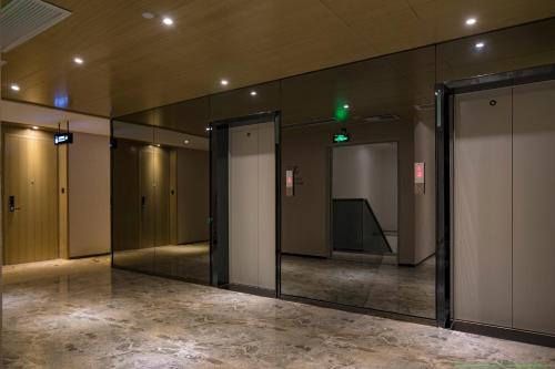 a hallway with doors and mirrors in a building at Paco Hotel Tiyuxilu Metro Guangzhou-Free Shuttle Bus during Canton Fair&5 Min walk to Canton Fair Buyer Registration Store in Guangzhou
