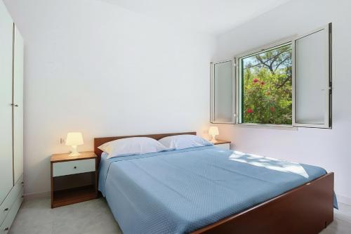 a bedroom with a blue bed and a window at Villaggio Sabbia d'oro in Lupetto