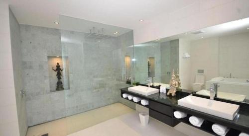 Un baño con dos lavabos y un espejo grande. en Sansuri Resort, en Surin Beach