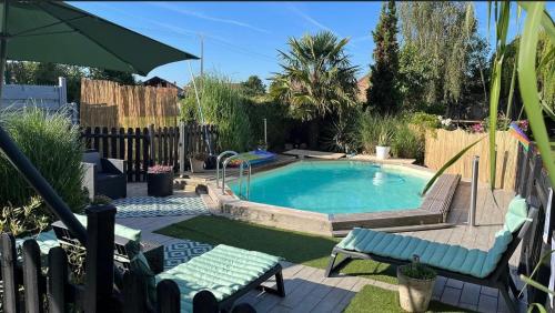a swimming pool in a yard with chairs and an umbrella at Demeure de caractère du Nord in Ostricourt