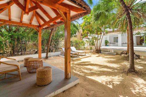 a patio with a wooden pavilion and chairs and palm trees at Villa Kayou by Sealodge Mauritius in Tamarin
