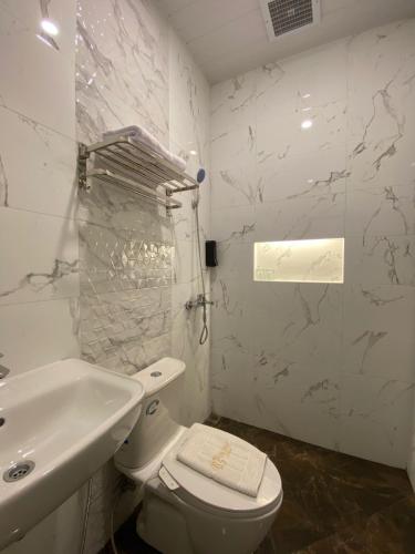 a white bathroom with a toilet and a sink at The Bali Hotel in Sumedang Utara