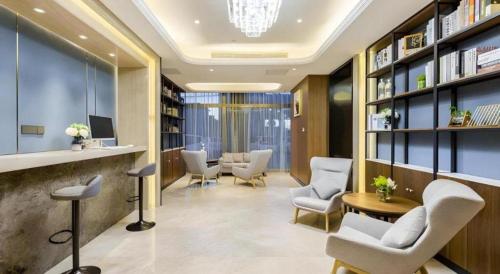 una sala de espera con sillas, mesa y libros en Yitel Collection Beijing Capital Airport New International Exhibition, en Beijing