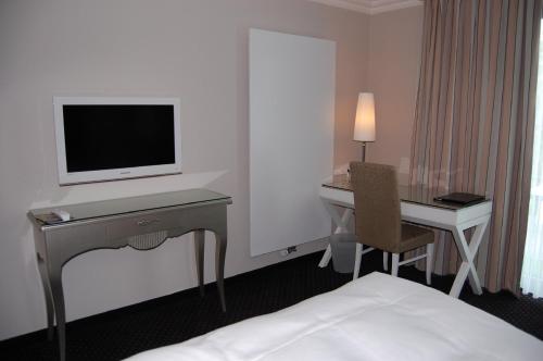 a hotel room with a desk and a television and a bed at Hotel & Restaurant Schönau in Peine