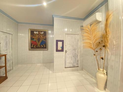 a bathroom with a painting and a vase with a plant at Twin Inn in Ubud