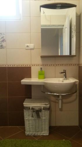 a bathroom with a sink and a mirror and a basket at House Lavanda in Rab