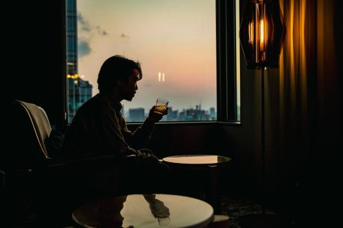 a man sitting in a chair looking out a window at The Gate Hotel Fukuoka by Hulic in Fukuoka