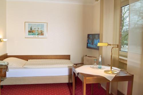 
a hotel room with a bed, desk, chair and a television at Hotel Restaurant Witte in Ahlen
