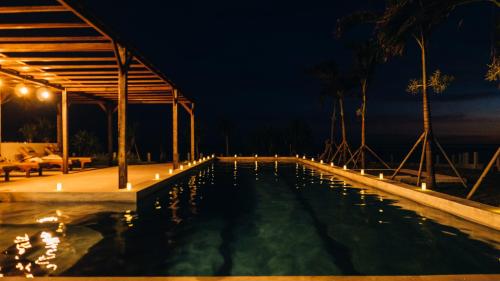 レンボンガン島にあるNaluna Lembonganの夜間のヤシの木と照明のスイミングプール