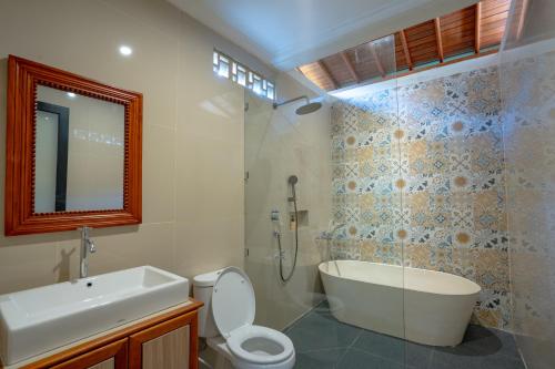 a bathroom with a tub and a toilet and a sink at Gusti family guest house in Tegalalang