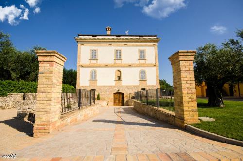 a large white building with a gate and a fence at Il Casino di Remartello in Loreto Aprutino