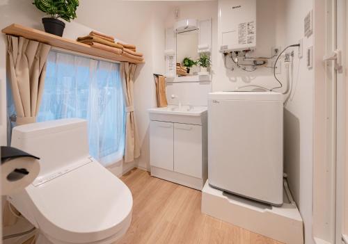 a white bathroom with a toilet and a sink at Hotel the World Omori in Tokyo