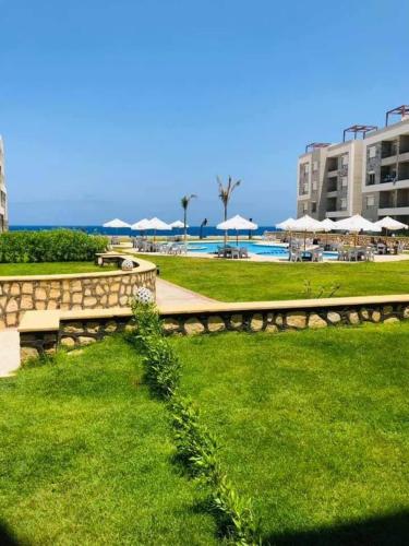 un parc avec un banc et une piscine avec des parasols dans l'établissement Long Island Resort -C05 - Family only, à Marsa Matruh