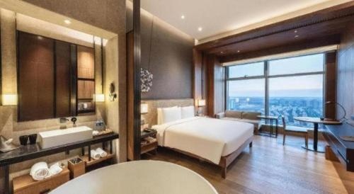 a bedroom with a bed and a bathroom with a view at AOLUGUYA in Harbin
