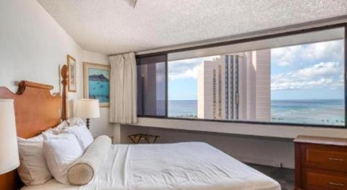 a bedroom with a large window with a view of the ocean at Marina Tower Waikiki in Honolulu