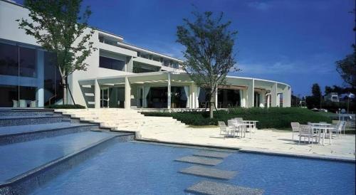 a building with tables and chairs next to a swimming pool at Hotel Harvest Hamanako in Hamamatsu