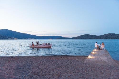 a boat on the water next to a dock at Elounda Akti Olous (Adults Only) in Elounda