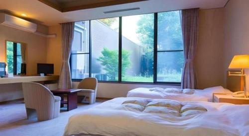 Un dormitorio con dos camas y una gran ventana. en Yufuin Onsen Yufuin Nanairo no Kaze, en Yufu