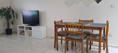 a dining room with a table with chairs and a tv at iris appart vue dégagée, bon emplacement in Sale
