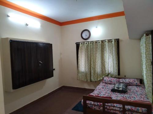 a bedroom with a bed and a clock on the wall at Roopa Studio in Mysore