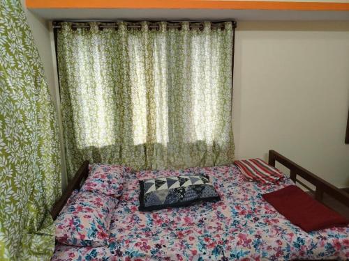 a bedroom with a bed and a window with curtains at Roopa Studio in Mysore