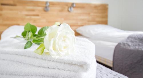 a white rose sitting on top of a pile of towels at Grimstad Vertshus in Grimstad