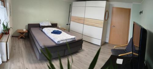 a small bedroom with a bed and a chair at Geräumiges Zimmer mit Doppelbett, Bad und Küche in Michelfeld