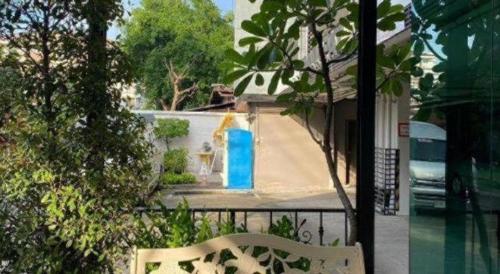 a white bench next to a building with a blue door at Pannapat Place in Bangkok