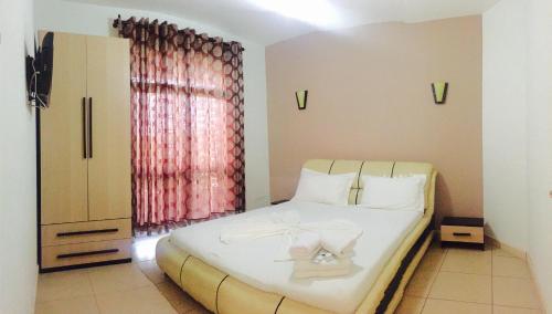 1 dormitorio con cama y ventana en Godija Hotel & Suites, en Velipojë
