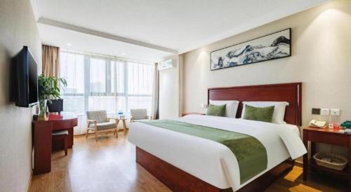 a hotel room with a large bed and a desk at GreenTree Inn Tianjin JinNan ShuangLin Metro Station Express Hotel in Tianjin